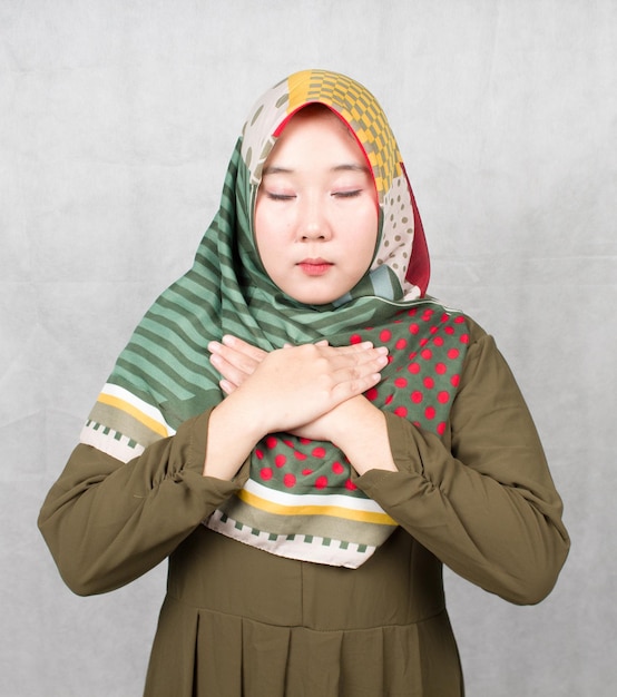 mulher muçulmana asiática de mãos dadas no peito. Mulher milenar emocional positiva se sente grata