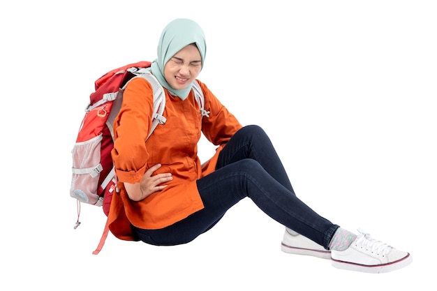 Mulher muçulmana asiática em um lenço na cabeça sentado com uma mochila sentindo dor de estômago