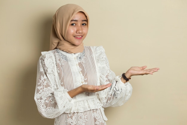 Mulher muçulmana asiática hijab com a mão apontando no espaço vazio