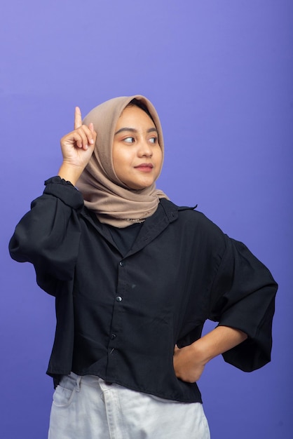 Mulher muçulmana asiática sorrindo enquanto levanta o gesto de mão, encontrando a ideia com espaço