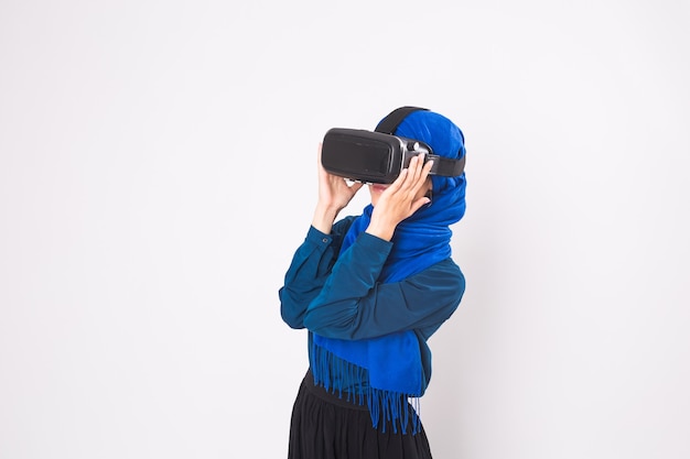 Mulher muçulmana asiática usando hijab usando óculos de fone de ouvido vr de realidade virtual em fundo branco.