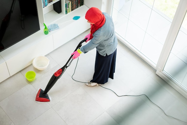 Mulher muçulmana feliz limpando a sala de estar da casa moderna. foto de alta qualidade