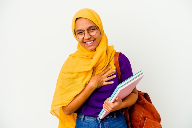 Mulher muçulmana jovem estudante vestindo um hijab isolado no fundo branco, rindo e se divertindo.