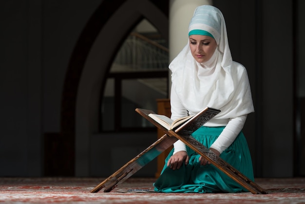 Mulher muçulmana lendo livro islâmico sagrado Alcorão