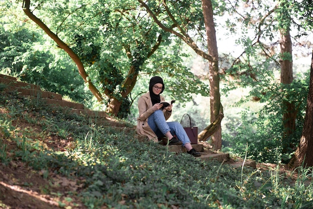 Mulher muçulmana lendo um livro no parque nas horas vagas