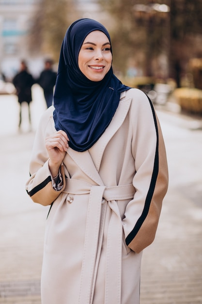 Mulher muçulmana moderna com lenço na cabeça, andando na rua