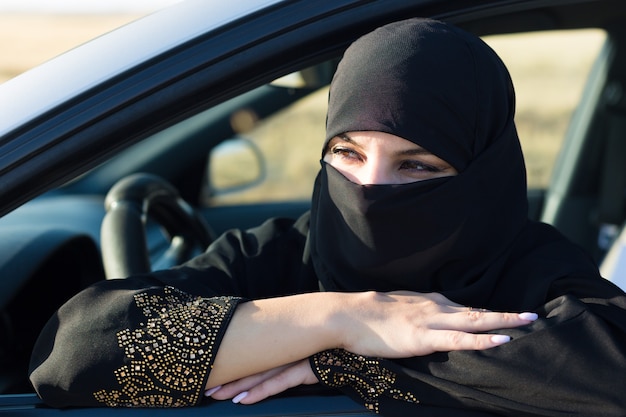 Mulher muçulmana na fila de espera no engarrafamento.