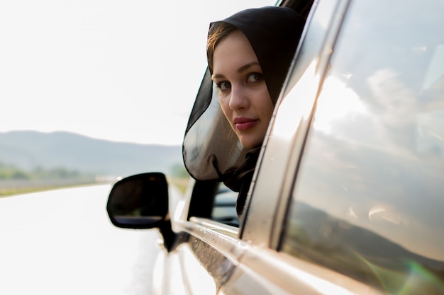 Foto mulher muçulmana, olhando para fora da janela do carro