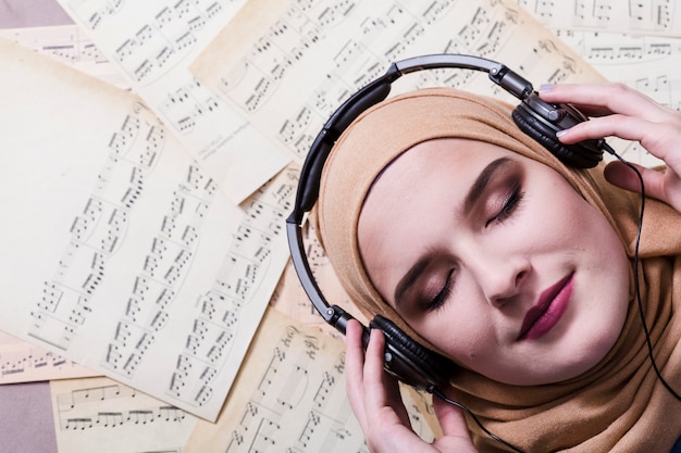 Foto mulher muçulmana ouvindo música em fones de ouvido