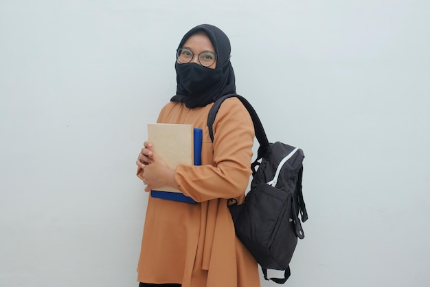 Mulher muçulmana segurando livro e bolsa