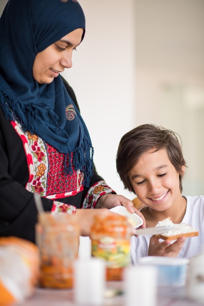 Mulher muçulmana tradicional com filho na cozinha