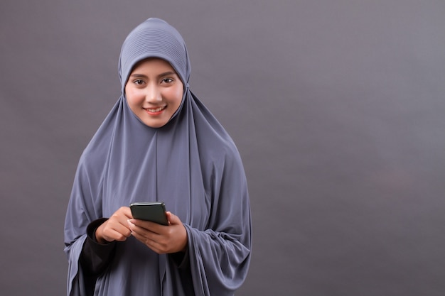 Mulher muçulmana usando smartphone, dispositivo de internet sem fio