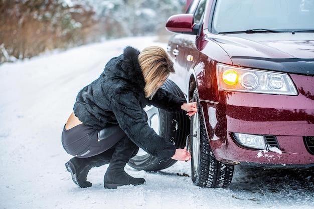 Mulher mudando o pneu perfurado de seu carro no inverno Menina bonita substituindo pneus