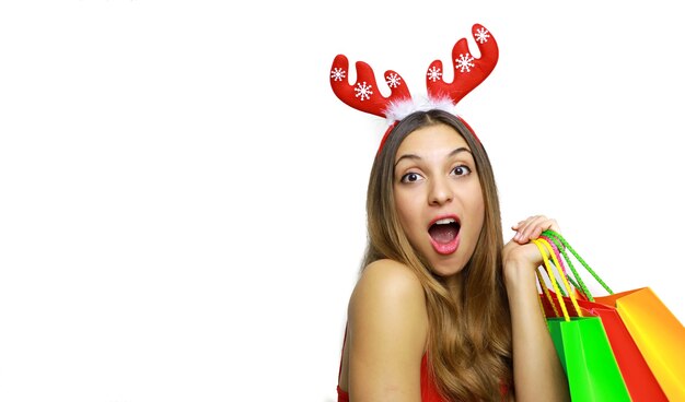 Foto mulher muito alegre com chifres de rena e sacolas de compras