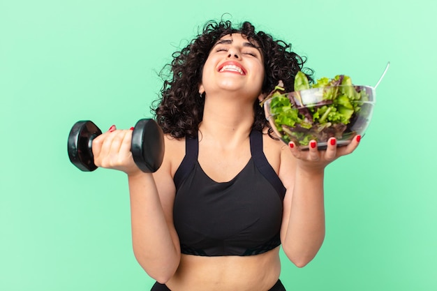 Mulher muito árabe com um haltere e uma salada. conceito de fitness