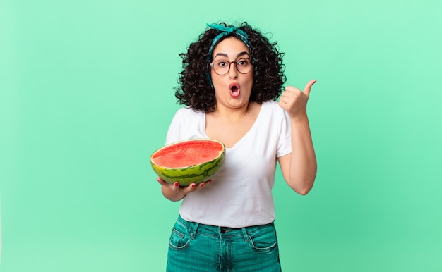 Mulher muito árabe olhando espantada com a descrença e segurando uma melancia. conceito de verão