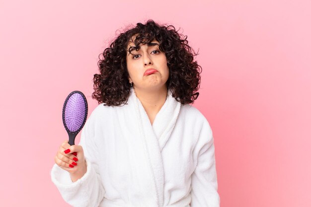 Mulher muito árabe vestindo roupão de banho e segurando uma escova de cabelo