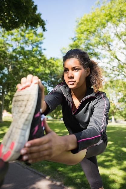 Mulher muito esportiva que estica sua perna no parque