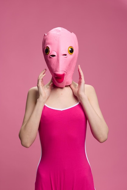 Mulher muito estranha em uma máscara de peixe de silicone rosa para imagem louca de Halloween em roupas cor de rosa