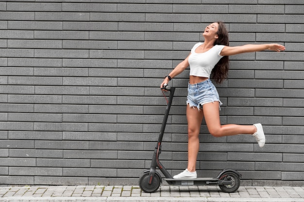 Mulher muito feliz posando em scooter elétrico