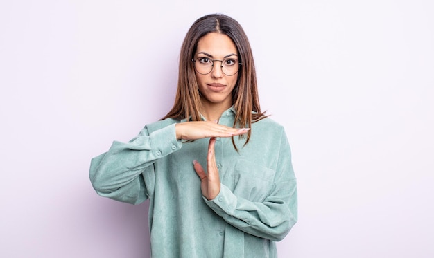 Mulher muito hispânica parecendo séria, severa, irritada e descontente, fazendo sinal de tempo limite