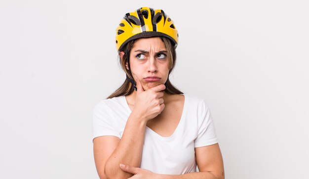 Mulher muito hispânica pensando sentindo o conceito de bicicleta duvidoso e confuso