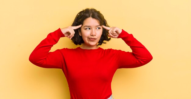 Mulher muito hispânica se sentindo confusa ou duvidando concentrando-se em uma ideia pensando muito procurando copiar o espaço ao lado