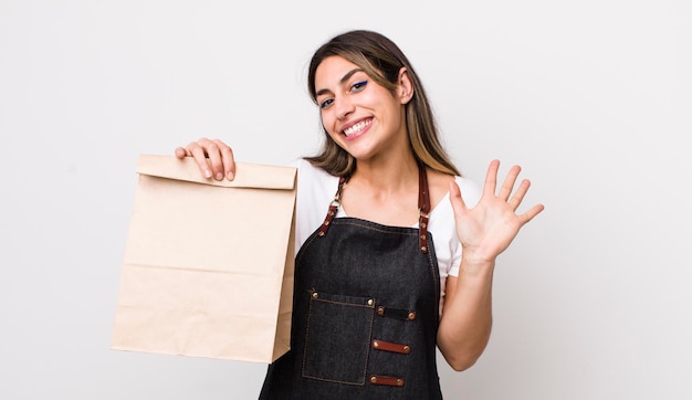 Mulher muito hispânica sorrindo alegremente acenando com a mão dando as boas-vindas e cumprimentando sua entrega e levando o conceito