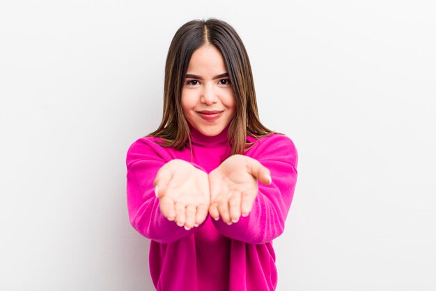 Mulher muito hispânica sorrindo alegremente com um olhar positivo confiante e amigável oferecendo e mostrando um objeto ou conceito