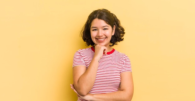 Mulher muito hispânica sorrindo curtindo a vida se sentindo feliz amigável satisfeita e despreocupada com a mão no queixo