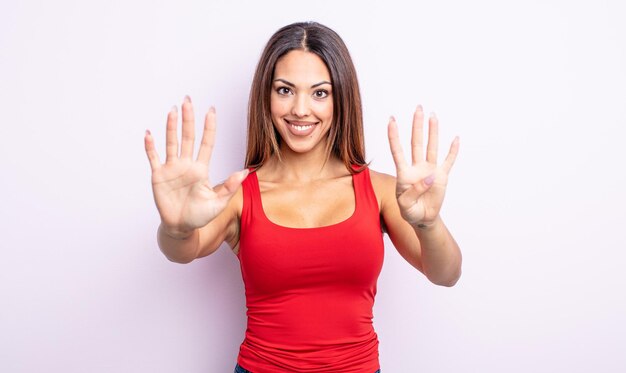 Mulher muito hispânica sorrindo e parecendo amigável, mostrando o número nove ou nono com a mão para a frente, em contagem regressiva