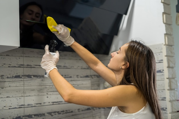 Mulher muito magra em luvas de proteção com um pano de limpeza geral na cozinha. tarefas domésticas