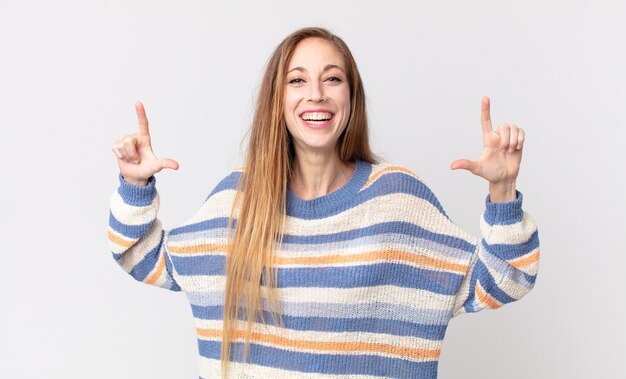 Mulher muito magra emoldurando ou delineando seu próprio sorriso com as duas mãos, parecendo positiva e feliz, conceito de bem-estar