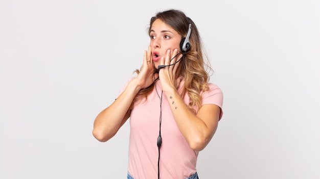 Mulher muito magra se sentindo feliz, animada e surpresa assistente de operador com um fone de ouvido