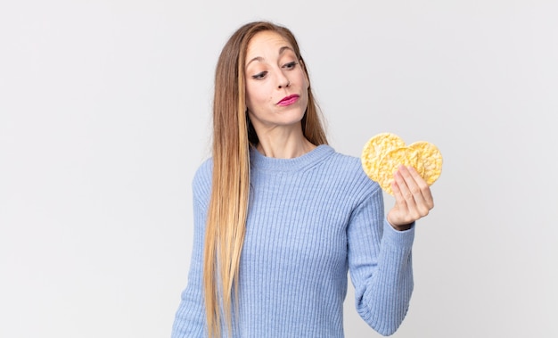 Mulher muito magra segurando um bolo de dieta de arroz