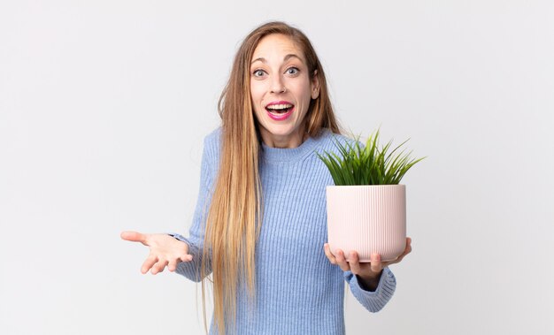 Mulher muito magra segurando uma planta decorativa