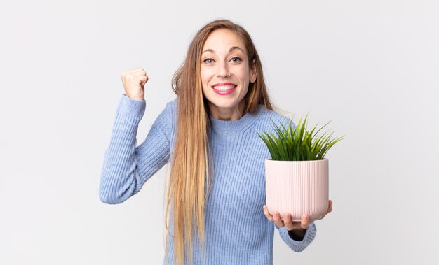 Mulher muito magra segurando uma planta decorativa