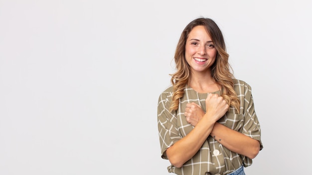 Mulher muito magra sorrindo alegremente e comemorando, com os punhos cerrados e os braços cruzados, sentindo-se feliz e positiva