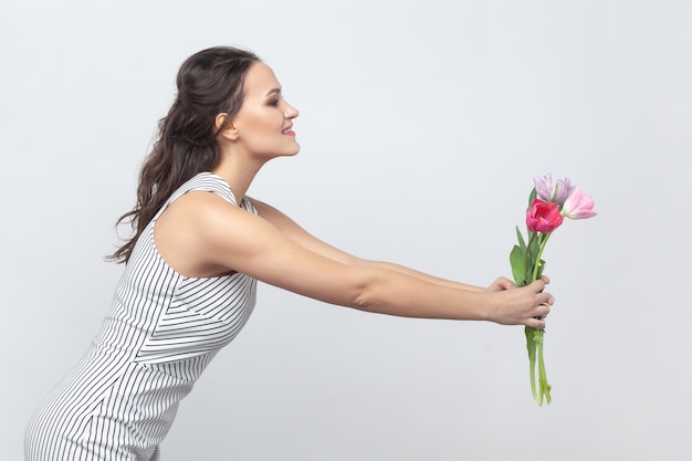 Mulher muito positiva segurando um buquê de tulipas dando para a mãe parabenizando em março