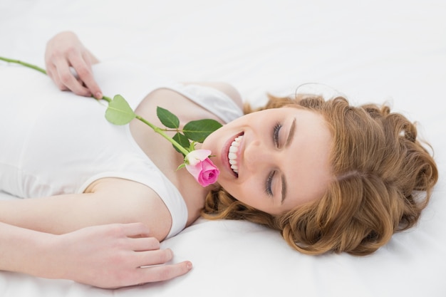 Mulher muito relaxada descansando na cama com rosa
