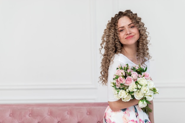 Mulher muito romântica segurando um buquê de flores e sorrindo suavemente olhando para a câmera