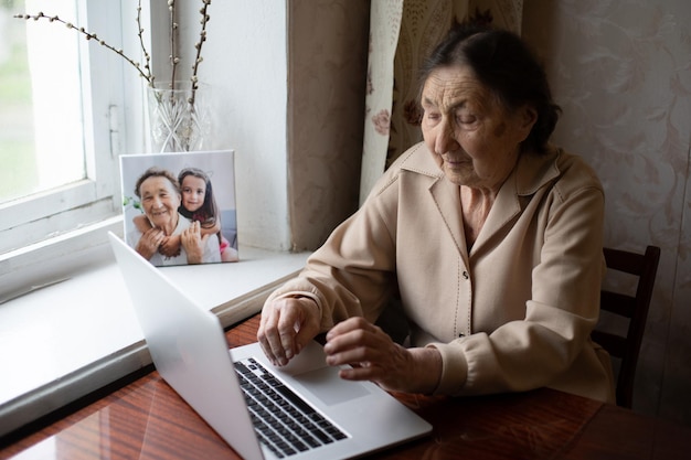 mulher muito velha usando laptop sentado em casa.