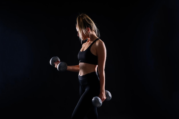 Mulher musculosa fazendo exercícios com halteres no bíceps foto de mulher forte isolada no estúdio