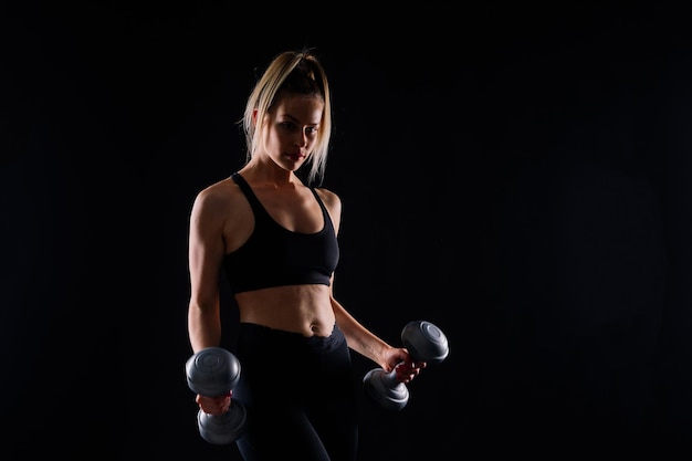 Mulher musculosa fazendo exercícios com halteres no bíceps foto de mulher forte isolada no estúdio