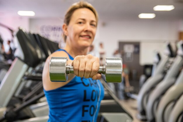 Mulher na academia com halteres mantendo a forma