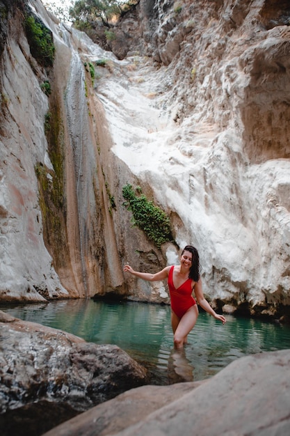 Mulher na cachoeira de Dimosari do maiô vermelho no marco famoso da Grécia da ilha de Lefkada