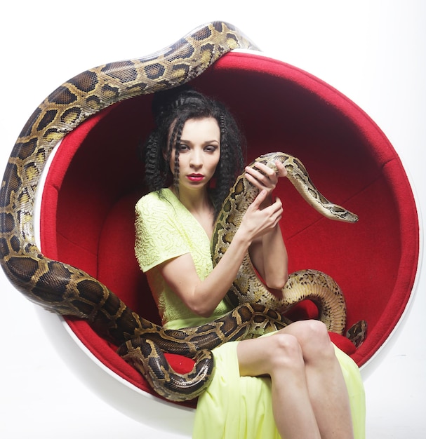 Foto mulher na cadeira vermelha holdung python