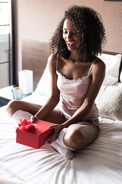 Mulher na cama com um presente no dia dos namorados ou aniversário