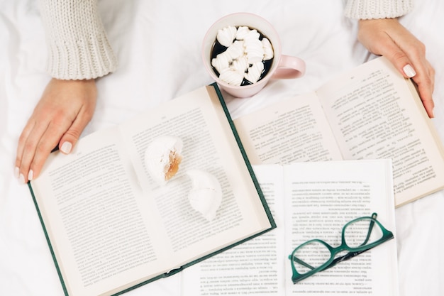 Mulher na cama lendo um livro com uma xícara de café. Foto elegante e minimalista.