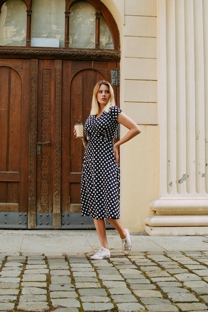 Foto mulher na cidade com um copo de café no fundo da porta